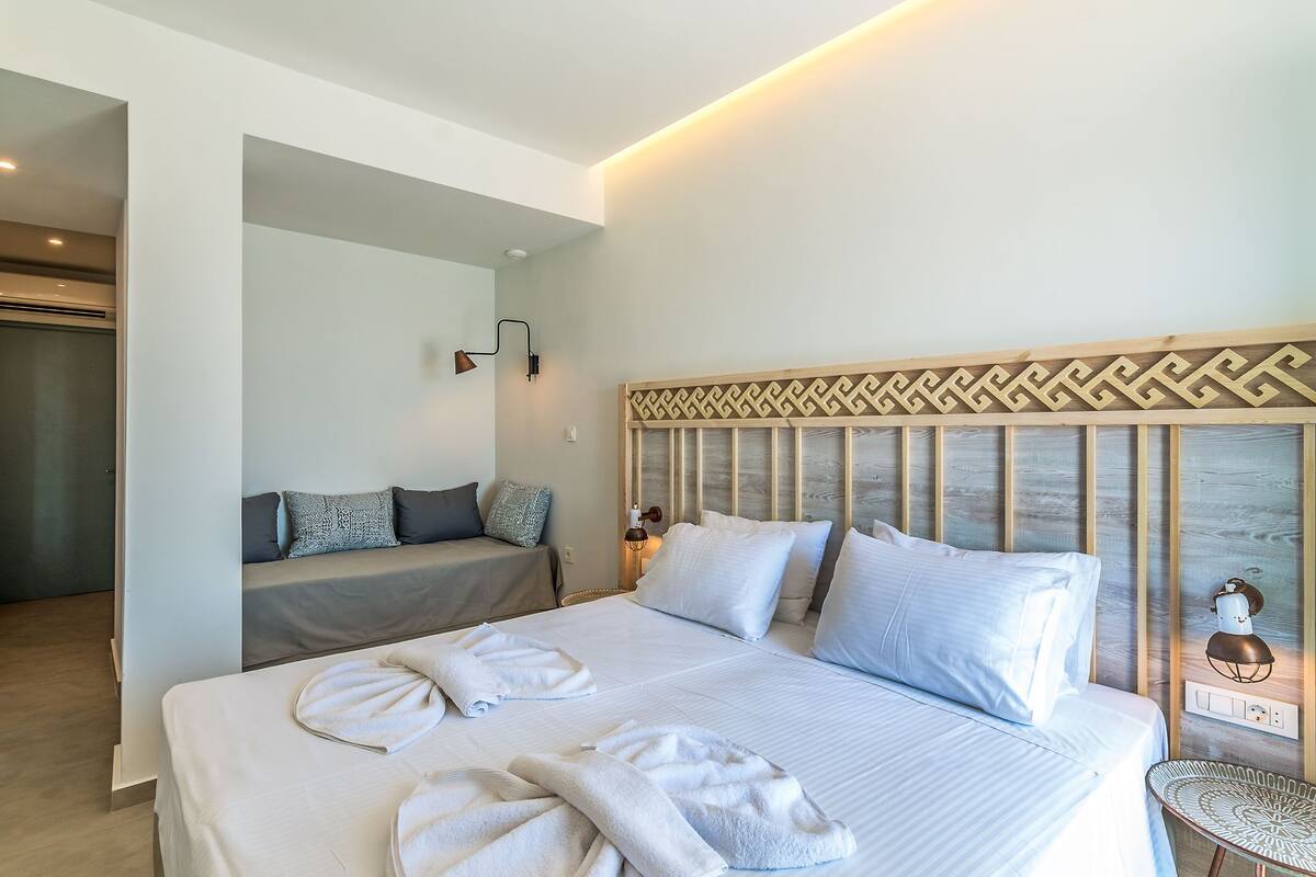 A modern hotel room with a large bed, a sofa, and a small table.