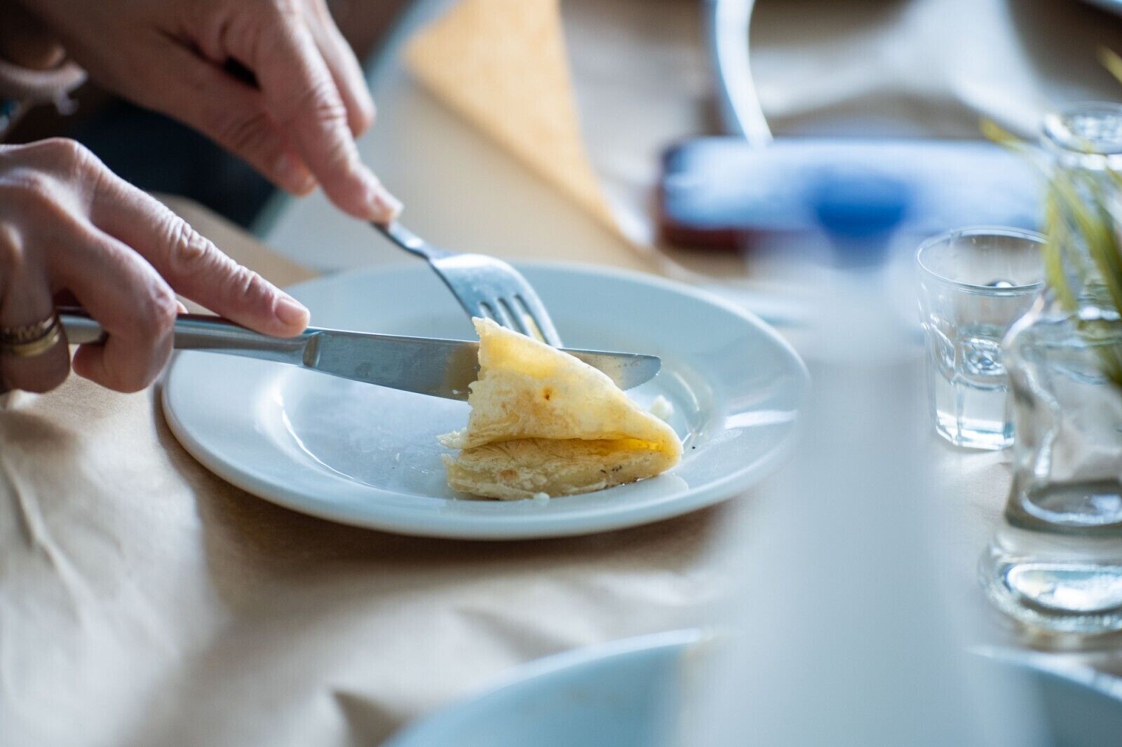 Una persona cortando un trozo de pastel en un plato blanco.