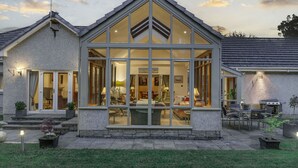 A modern house with a large glass front, stone exterior, and a well-lit patio area. - 'The Willows' A Charming home on Dollarbeg Castle Estate (Dollar)