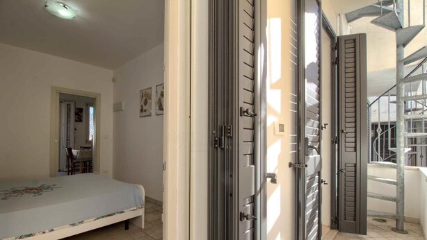 Un dormitorio con cama, una puerta y una escalera que da al exterior.