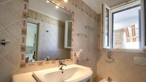 Un baño con un espejo grande, un lavamanos, un bidé y una ventana.