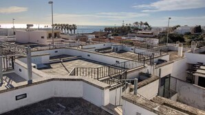 Una terraza en la azotea con vista al mar, rodeada de edificios.