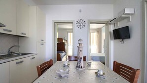 Cocina compacta con pileta, alacenas y un comedor con una mesa para dos.