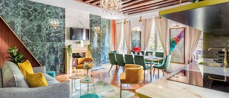 Una sala de estar moderna con chimenea, un comedor con sillas verdes y una cocina con pileta de acero inoxidable.