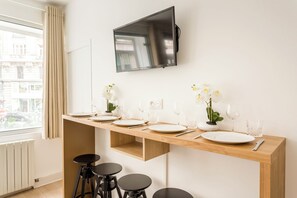 Una cocina moderna con encimera de madera, un televisor montado arriba y una ventana con cortinas.