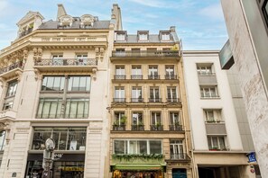Un edificio de varios pisos con detalles arquitectónicos ornamentales, incluyendo balcones y molduras decorativas.
