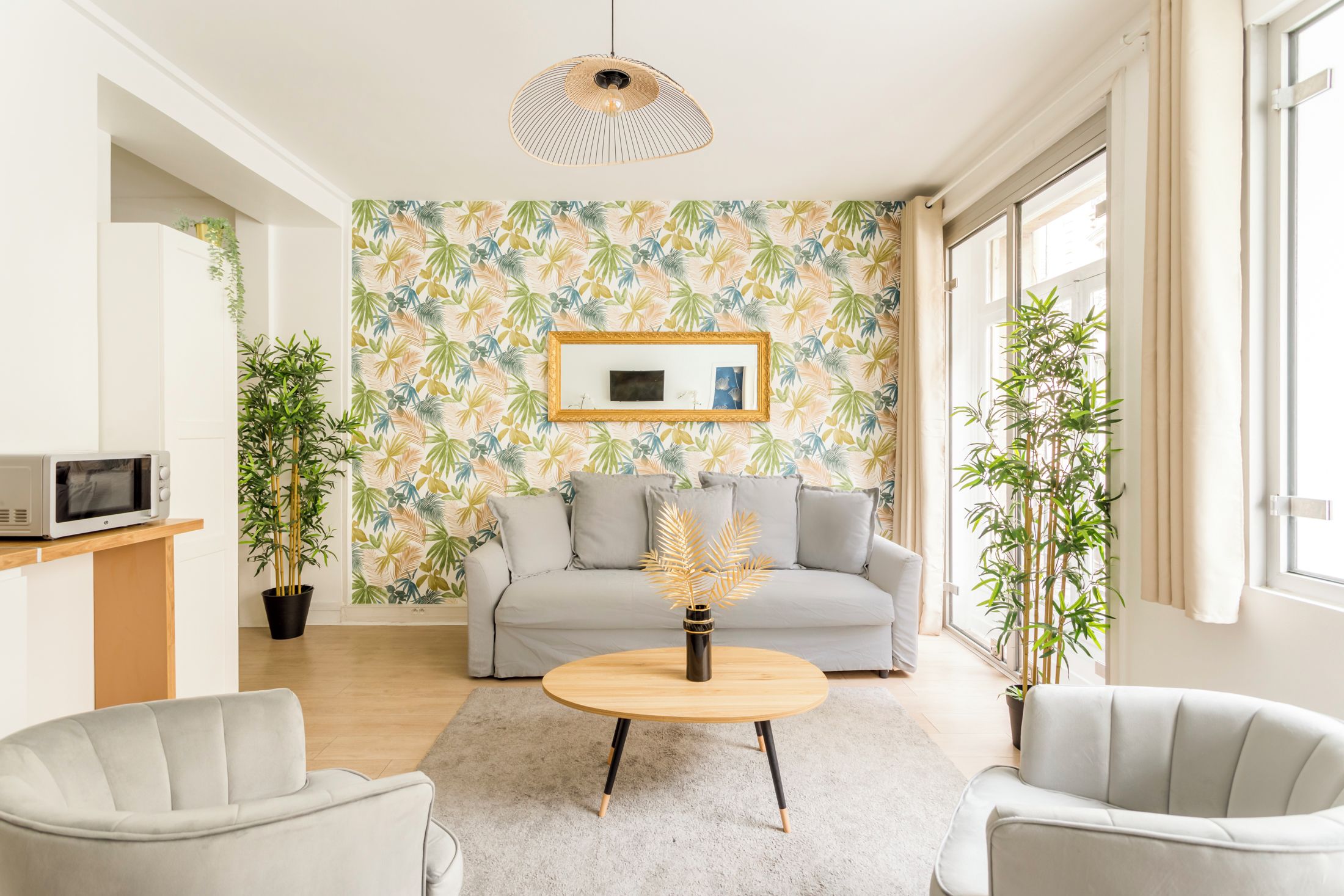 A modern living room with a sofa, two armchairs, a coffee table, and a potted plant.