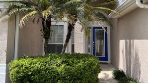 A house with a covered porch, a blue door, and a palm tree. - Relaxing Modern 3 br home with HEATED POOL (Palm Coast)