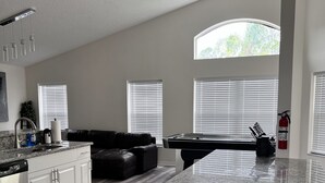 A spacious kitchen with a granite countertop, a black leather couch, and a dining area with a pool table. - Relaxing Modern 3 br home with HEATED POOL (Palm Coast)
