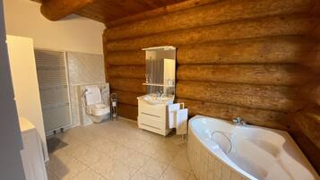 A log cabin bathroom with a toilet, sink, and bathtub.
