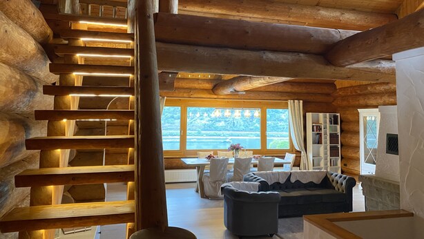 Ein Holzinnenraum mit einer Wendeltreppe, einem Sofa und Seeblick.