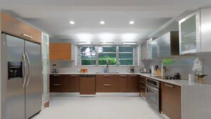 Eine moderne Küche mit Edelstahlgeräten, Holzschränken und einem großen Fenster, das für natürliches Licht sorgt.