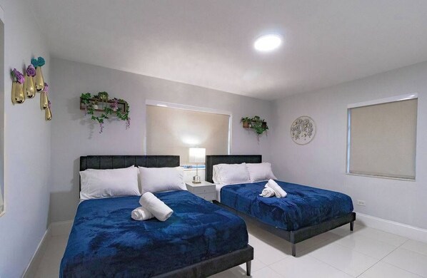 Habitación de hotel con dos camas, una mesita de noche, un espejo y detalles decorativos en la pared.