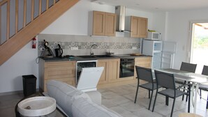 Una cocina moderna con armarios de madera, lavavajillas y un comedor con mesa y sillas.
