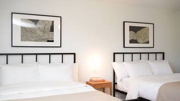 Une chambre d’hôtel avec deux lits, une table de chevet avec une lampe et deux œuvres d’art encadrées au mur.