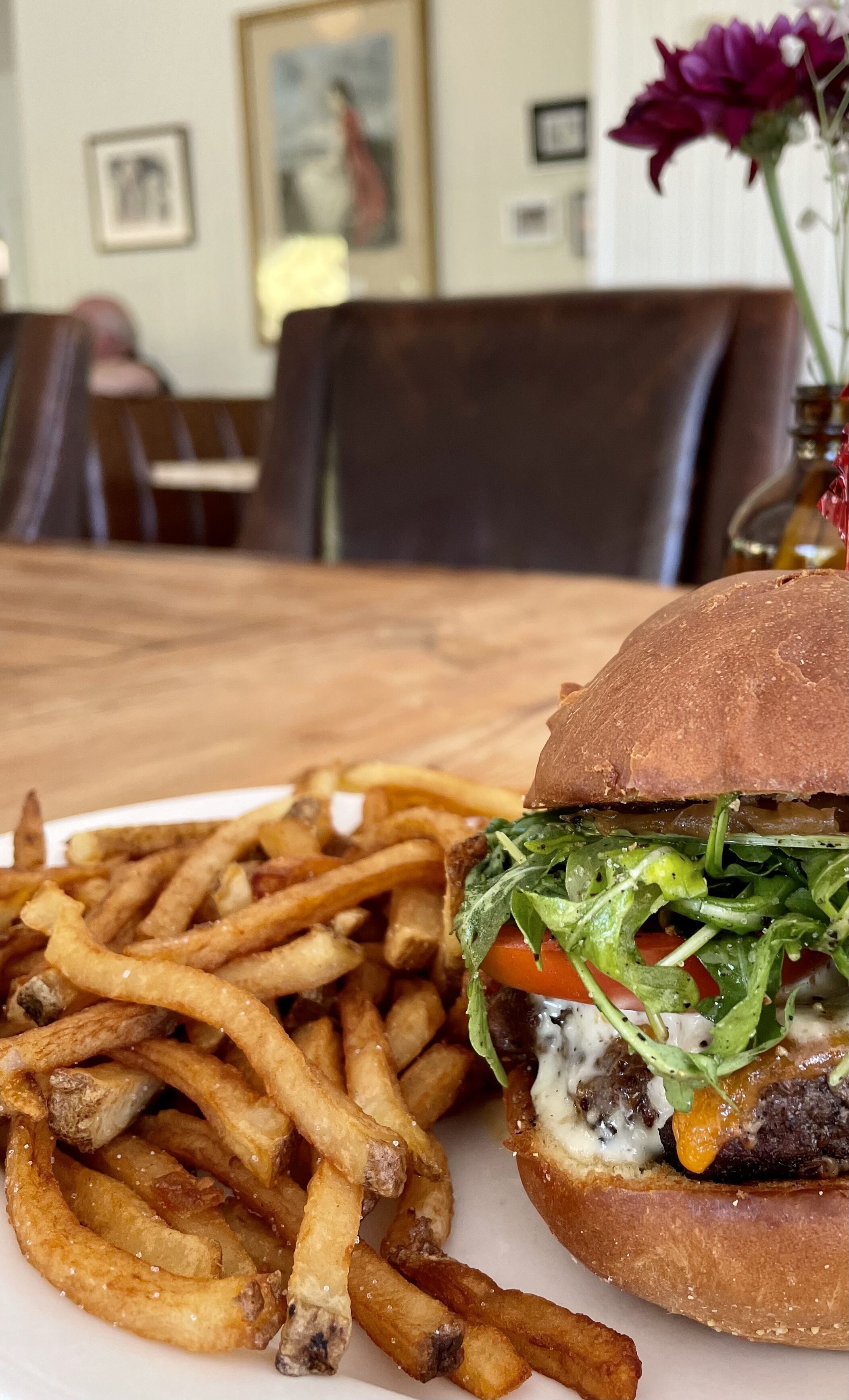 A meal consisting of a burger with lettuce, tomato, and cheese, alongside a plate of French fries.