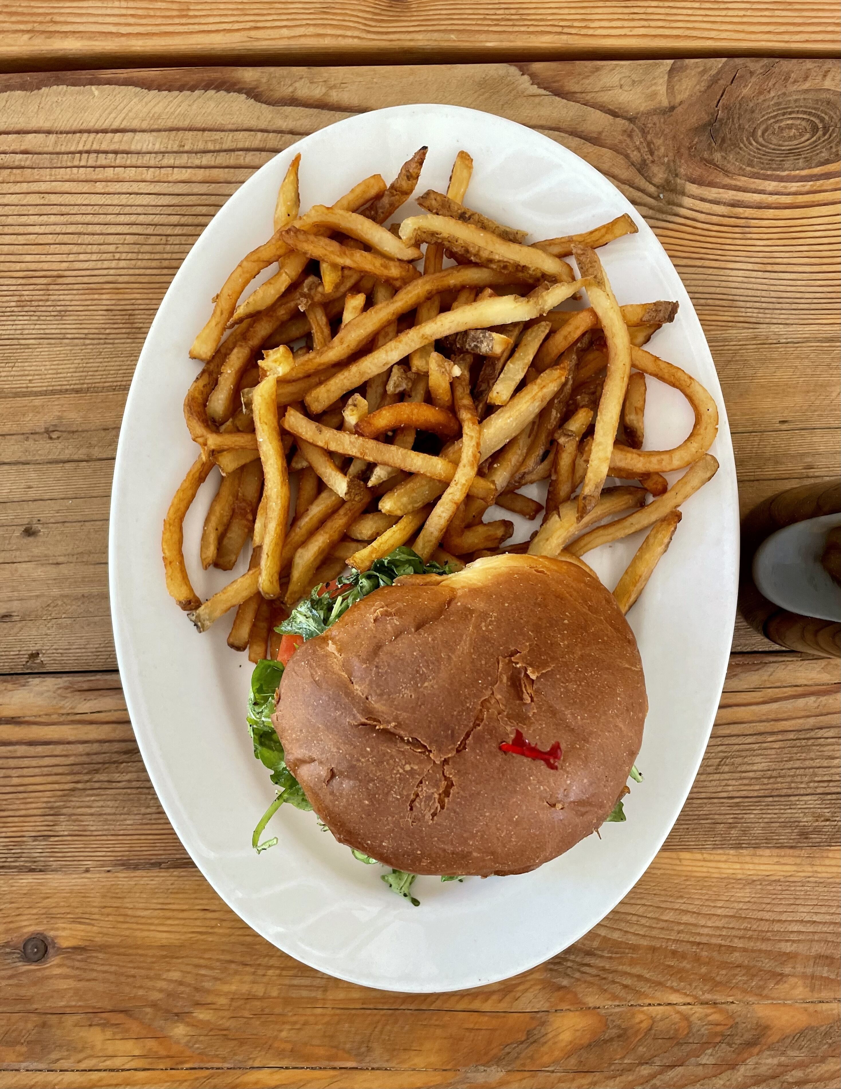 A plate of French fries and a burger on a wooden table.