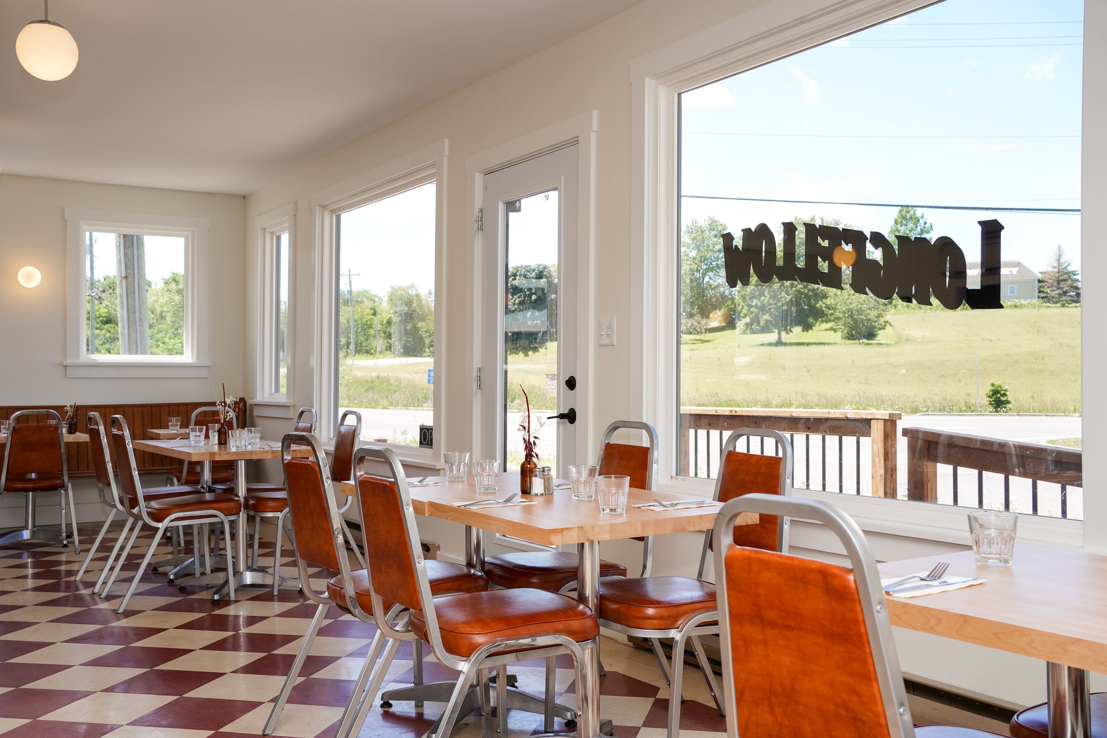 Comedor con piso a cuadros, sillas de estructura metálica y vista a un campo de golf a través de amplios ventanales.