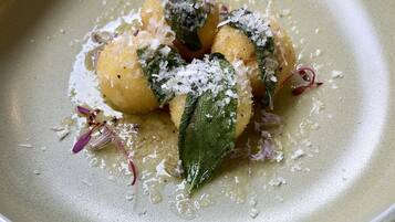 Un plato de comida de tonalidad verdosa, adornado con hierbas y posiblemente queso, sobre una superficie texturizada.