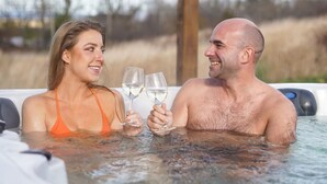 A couple in a hot tub with a wooden pergola overhead. - The Evangeline (Grand Pre)