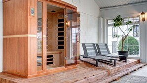 A sauna with a wooden exterior and glass doors, a bench, and a potted plant near a window. - The Evangeline (Grand Pre)