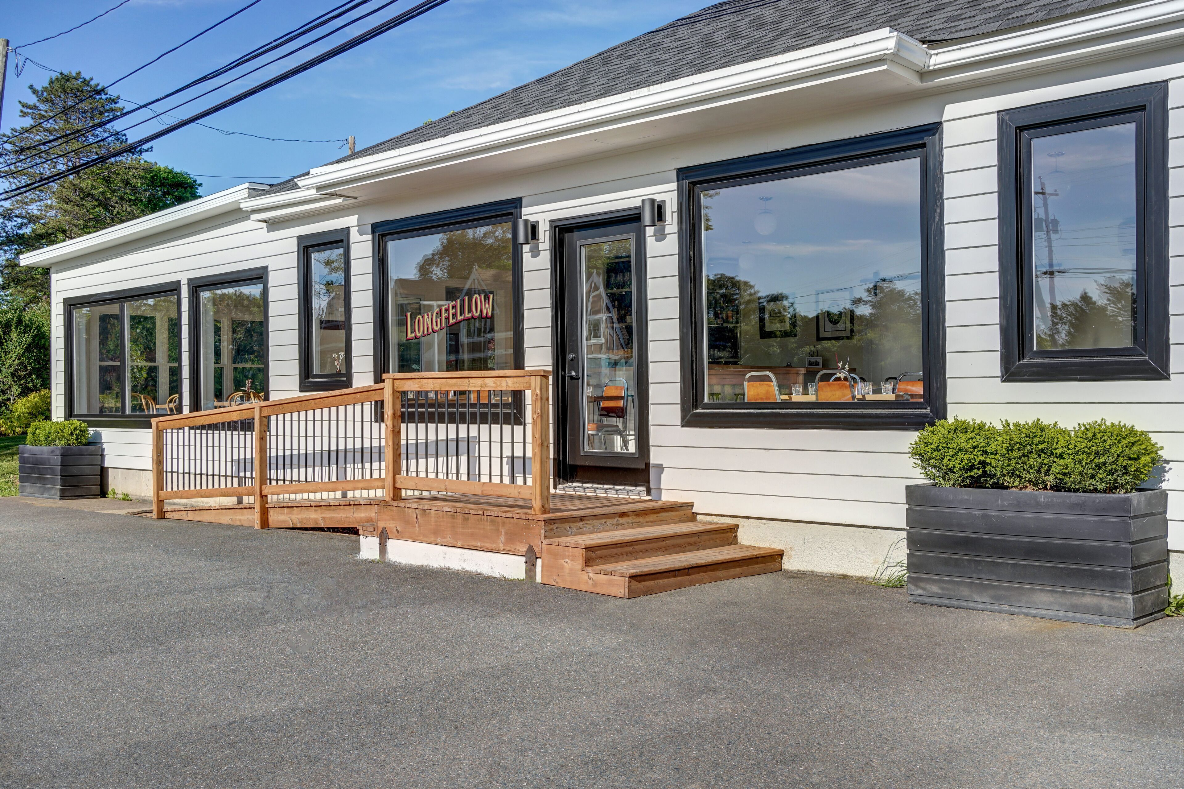 A building with large windows, a wooden porch, and a sign that reads "LONGFELLOW."