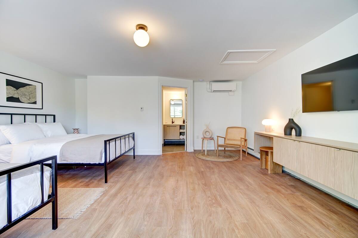 A modern bedroom with a bed, bedside table, chair, and a small desk area.