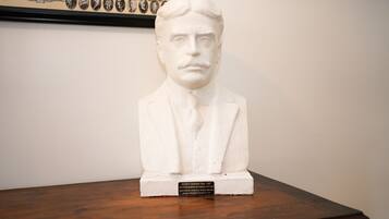 Une sculpture en buste, posée sur un socle en bois et agrémentée d’une plaque.