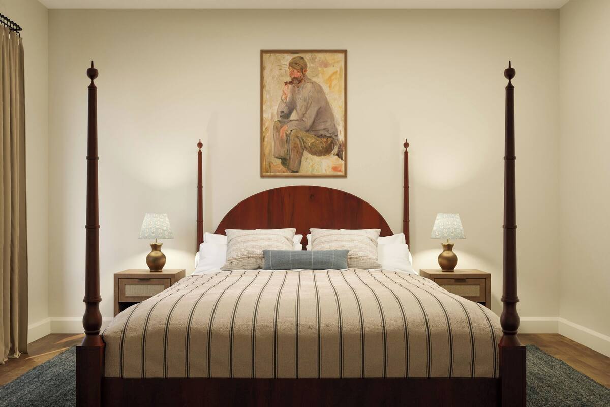 A four-poster bed with a striped bedspread, two bedside tables with lamps, a painting on the wall, and a dark carpet.