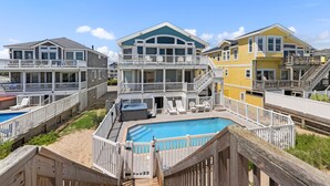 A beachfront property with multiple levels, a swimming pool, and a wooden deck. - Sand Pebbles: Oceanfront, Pool, Hot Tub, Rec Room (Nags Head)
