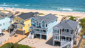 A beachfront property with multiple houses, a beach, and the ocean. - Sand Pebbles: Oceanfront, Pool, Hot Tub, Rec Room (Nags Head)