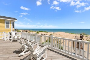 A wooden deck with white railings overlooking a beach. - Sand Pebbles: Oceanfront, Pool, Hot Tub, Rec Room (Nags Head)