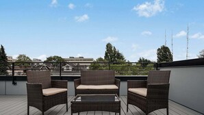 A rooftop terrace with wicker furniture and a glass table. - Perch - Urban Reflections 18: WS 97 | Cozy Home | Rooftop City View (Seattle)