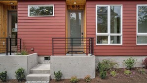 A red building with a wooden door labeled "1835," a concrete staircase, and small plants in front. - Perch - Urban Reflections 18: WS 97 | Cozy Home | Rooftop City View (Seattle)