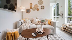 A modern living room with a grey sofa, a wooden coffee table, and a large window. - Perch - Urban Reflections 18: WS 97 | Cozy Home | Rooftop City View (Seattle)