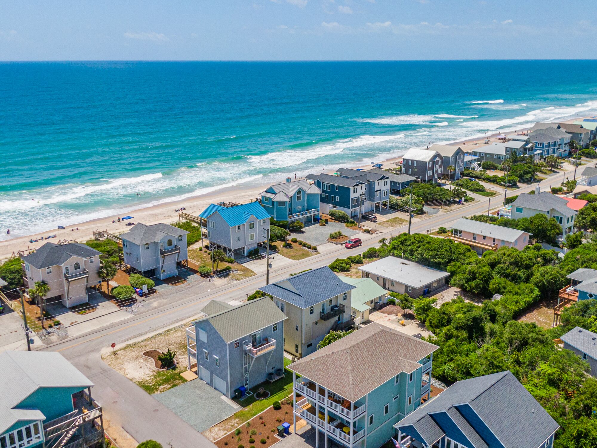 A coastal residential area with houses near the beach, featuring a mix of single and multi-story buildings, some with balconies.