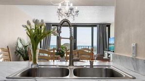 A kitchen with a double sink, a chandelier, and a view of the ocean.