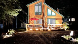 Une maison en bois à deux étages, dotée d’un patio couvert et d’un parasol rouge.