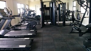 Une salle de sport équipée de tapis de course, de vélos elliptiques et de matériel de musculation.