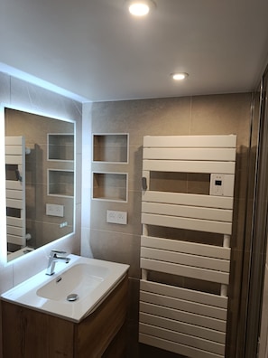 A modern bathroom with a large mirror, a white sink, and a built-in towel rack. - Arcs 1800 – Charming vacation rental right on the slopes – Sleeps 8–9 people. (Bourg-Saint-Maurice)
