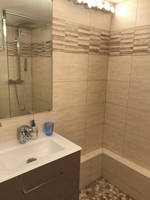 A bathroom with a shower, a sink with a mirror, and a blue cup. - Arcs 1800 - Charming apartment at the foot of the slopes - Sleeps 8–9. (Bourg-Saint-Maurice)