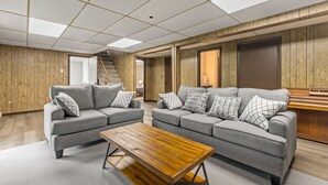 A modern living room with two grey sofas, a wooden coffee table, and a piano.