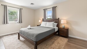 A bedroom with a bed, nightstands, and a window with curtains.