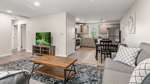 A modern living room with a wooden coffee table, a grey sofa, and a TV on a stand.