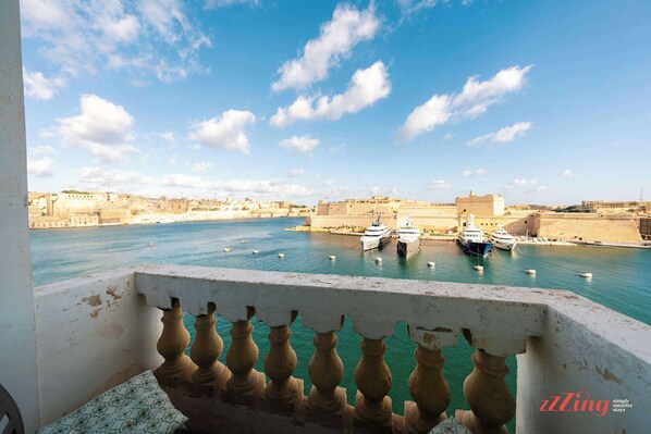 A balcony with a view of a harbor, boats, and a distant cityscape.