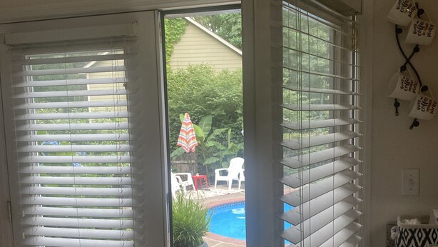 Une pièce dotée d’une porte-fenêtre coulissante donnant sur un jardin avec une piscine et du mobilier de jardin.