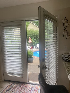A room with a sliding glass door leading to a backyard with a pool and patio furniture. - Kennesaw Garden Pool House-Stay close to everything; Lake Point, Braves, and KSU (Kennesaw)