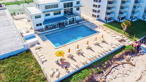 Un hôtel moderne doté d’une piscine sur le toit, de nombreux balcons et offrant une vue sur les bâtiments environnants.