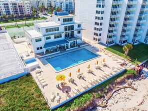 A modern hotel with a rooftop pool, multiple balconies, and a view of surrounding buildings. - Oceanfront Condo w/ Pool, Pickleball & Balcony! (New Smyrna Beach)
