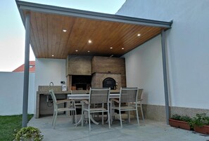 An outdoor patio with a wooden ceiling, a brick oven, and a dining table with chairs. - Nature Beach & Relax Plus (Illa de Arousa)
